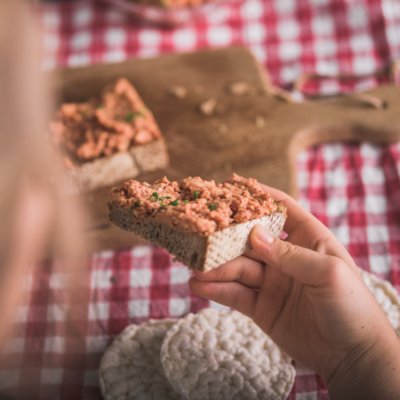 Jemand hält ein Schwarzbrot, bestrichen mit einem Reiswaffel-Aufstrich.