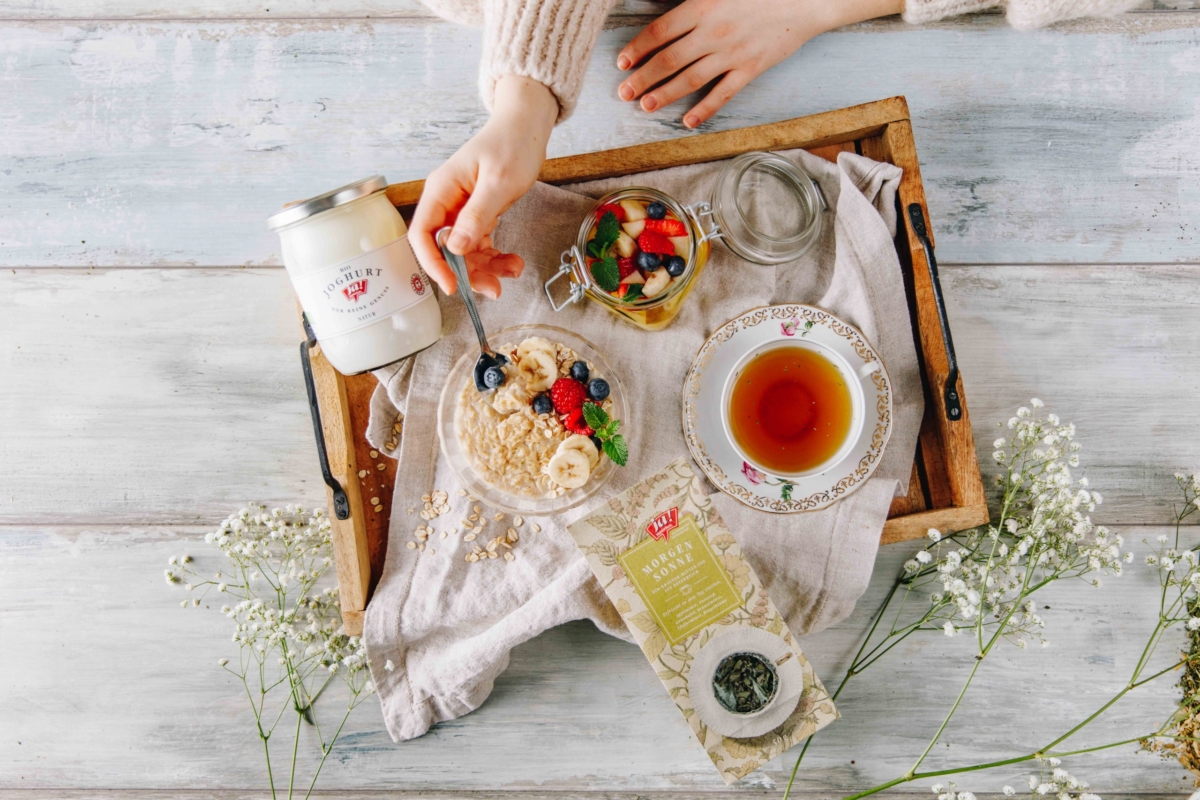 Frühstückstablett mit Ja! Natürlich Bio-Tee Morgensonne, Joghurt und frischem Obst.