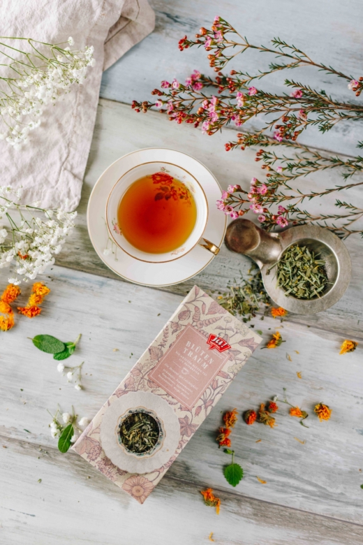 Eine Tasse Tee und einzelne Kräuter und eine Packung Ja! Natürlich Bio-Blütentraumtee.