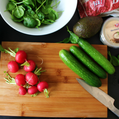 Bio-Radieschen und Gurken auf einem Holzbrett.