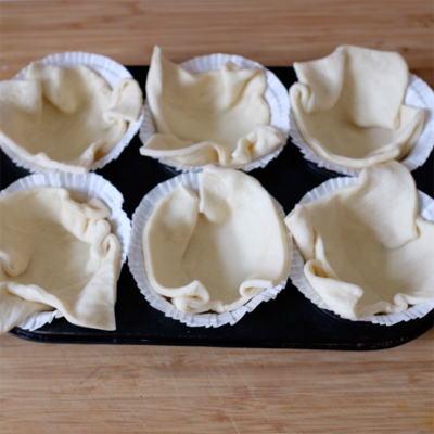 Pizzateig wurde in Muffinformen gesetzt.