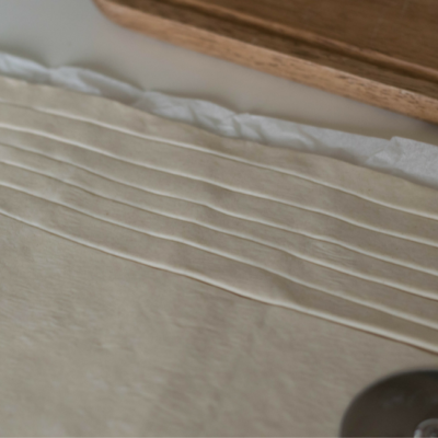 Jemand schneidet den Teig in feine Streifen.