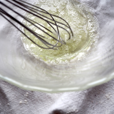 Jemand schlägt Bio-Eiklar mit dem Schneebesen auf.