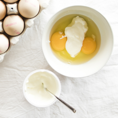 Zwei aufgeschlagene Bio-Eier in einer Schüssel mit Joghurt.