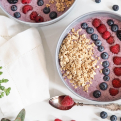 Lila Smoothiebowl in einer Schale, garniert mit Bio-Beeren.