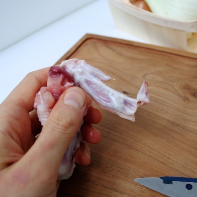 Jemand trennt die Flügel von einem Bio-Mini-Gockel.