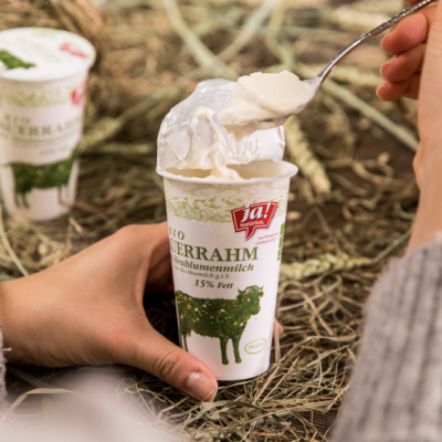 Jemand nimmt einen Löffel aus einem Becher Ja! Natürlich Bio-Sauerrahm.