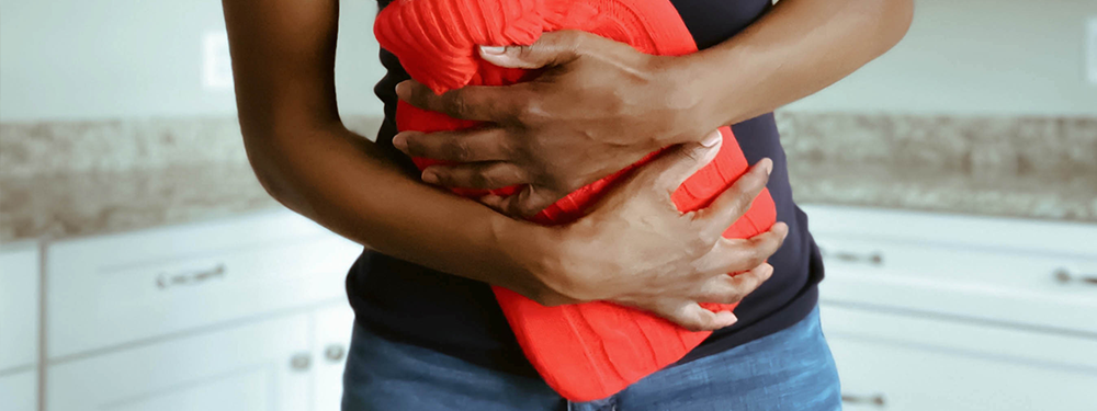 Frau mit Wärmflasche auf dem Bauch, Magazinbeitrag von Ja! Natürlich
