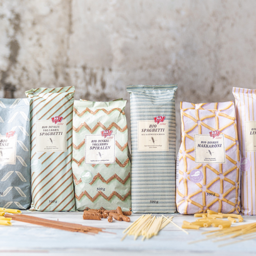 Bio-Fusilli, Bio-Dinkel Vollkorn Spahetti, Bio-Dinkel Vollkorn Spiralen, Bio Spaghetti, Bio Dinkel-Makkaroni und Bio-Dinkel Linguine von Ja! Natürlich stehen auf einem Tisch