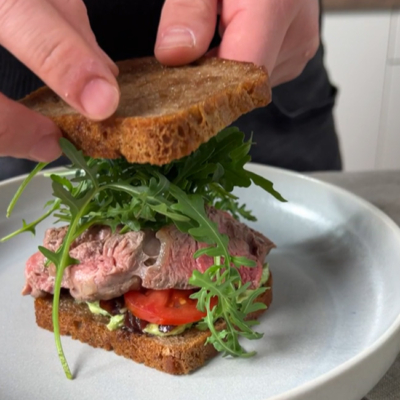 Fertiges Steak Sandwich mit Rucola, Tomaten und Kräuterbutter