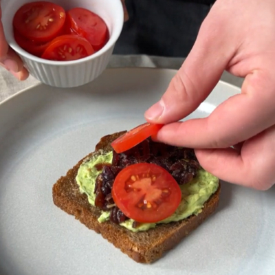 Bio-Brot wird mit Tomaten und Kräuterbutter belegt