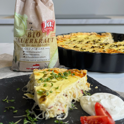 Bio-Sauerkrautquiche aufgeschnitten auf einem schwarzen Teller