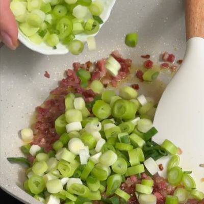 Bio-Speck und Lauchzwiebeln in einer Pfanne