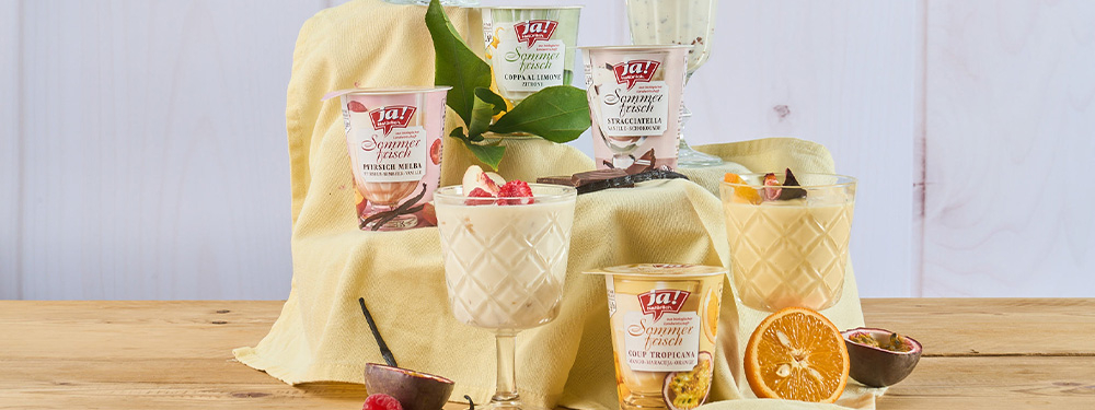 Bio-Sommerfrisch Joghurts auf gereiht in Gläser abgefüllt mit Früchten dekoriert