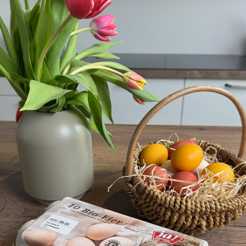 Gefärbte Ja! Natürlich Bio-Eier im Körbchen mit Tulpen