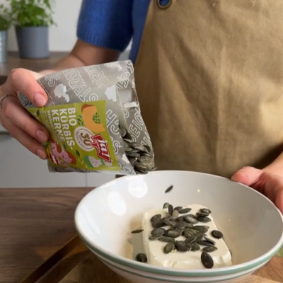 Bio-Frischkäse wird mit Kürbiskernen vermengt