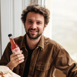 Produzent Simon Baur hält Ja! Natürlich Kombucha Flasche in der Hand