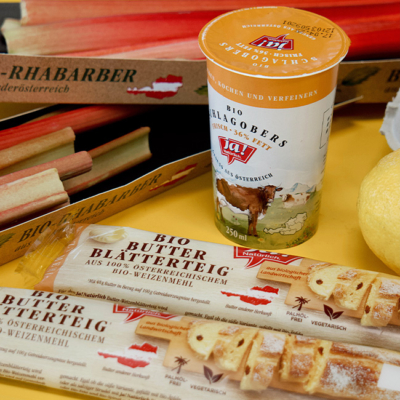 Zutaten wie Bio-Schlagobers, Bio-Blätterteig und Bio-Rhabarber auf einer Arbeitsfläche