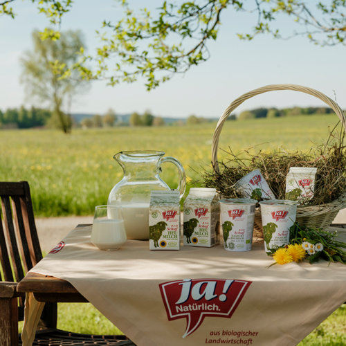 Ja! Natürlich Schafheumilchjoghurt und Schafheumilch auf einem tisch im Garten