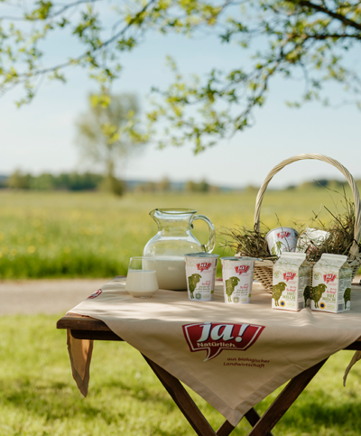 gedeckter Tisch im Garten mit Ja! Natürlich Bio-Schafheumilch-Produkten