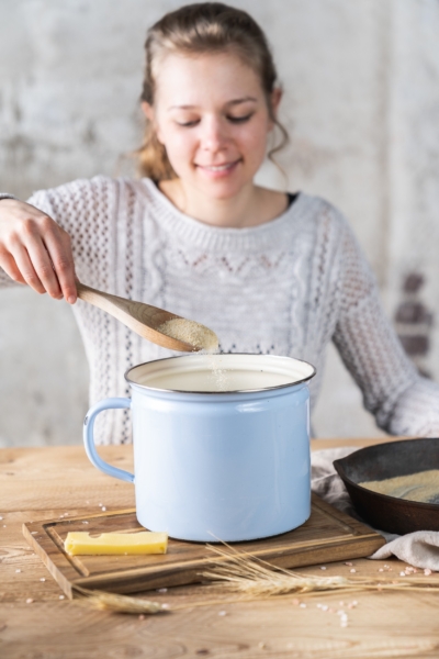 Jemand gibt Bio-Brösel in einen Topf.