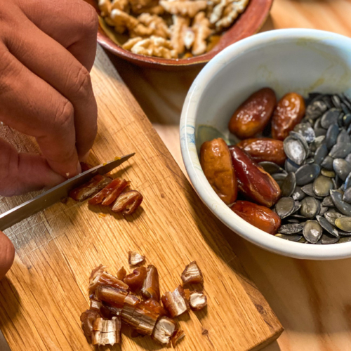 Datteln werden kleingeschnitten auf einem Holzbrett.