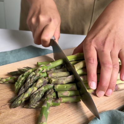 Grüner Spargel wird mit einem Messer kleingeschnitten!