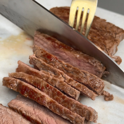 Bio-Steak auf einem Teller wird mit einem Messer in Scheiben geschnitten