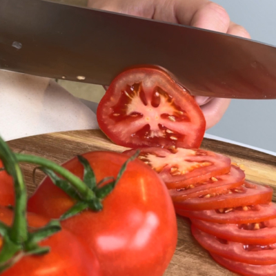 Bio-Tomaten werden in feine Scheiben geschnitten