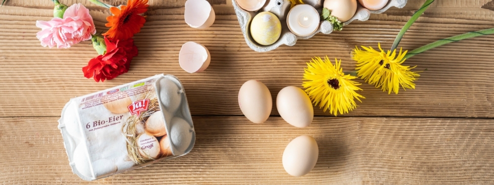 Eine Packung Ja! Natürlich Bio-Eier, daneben mehrere Eier am Tisch.