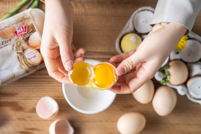 Jemand trennt das Eigelb von Bio-Eiern.
