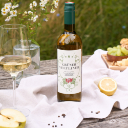 Flasche Grüner Veltliner mit Äpfeln und Zitronen im Hintergrund Weintrauben