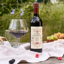 Bio-Wein Sankt Laurent in einem Glas. Davor Beeren und frische Früchte