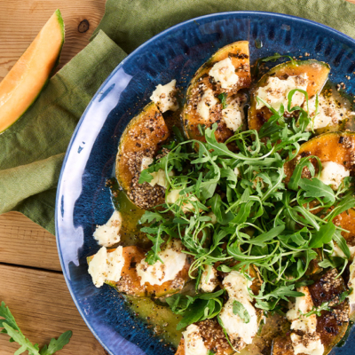 Bio-Grillmelone auf einem Teller angerichtet mit Mozzarella und Rucola