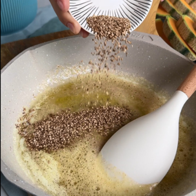 Sesam wird in eine Pfanne mit Butter gegeben und geröstet.