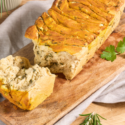 Fertiges, fluffiges Zupfbrot mit Kräutern auf einem Brett angerichtet