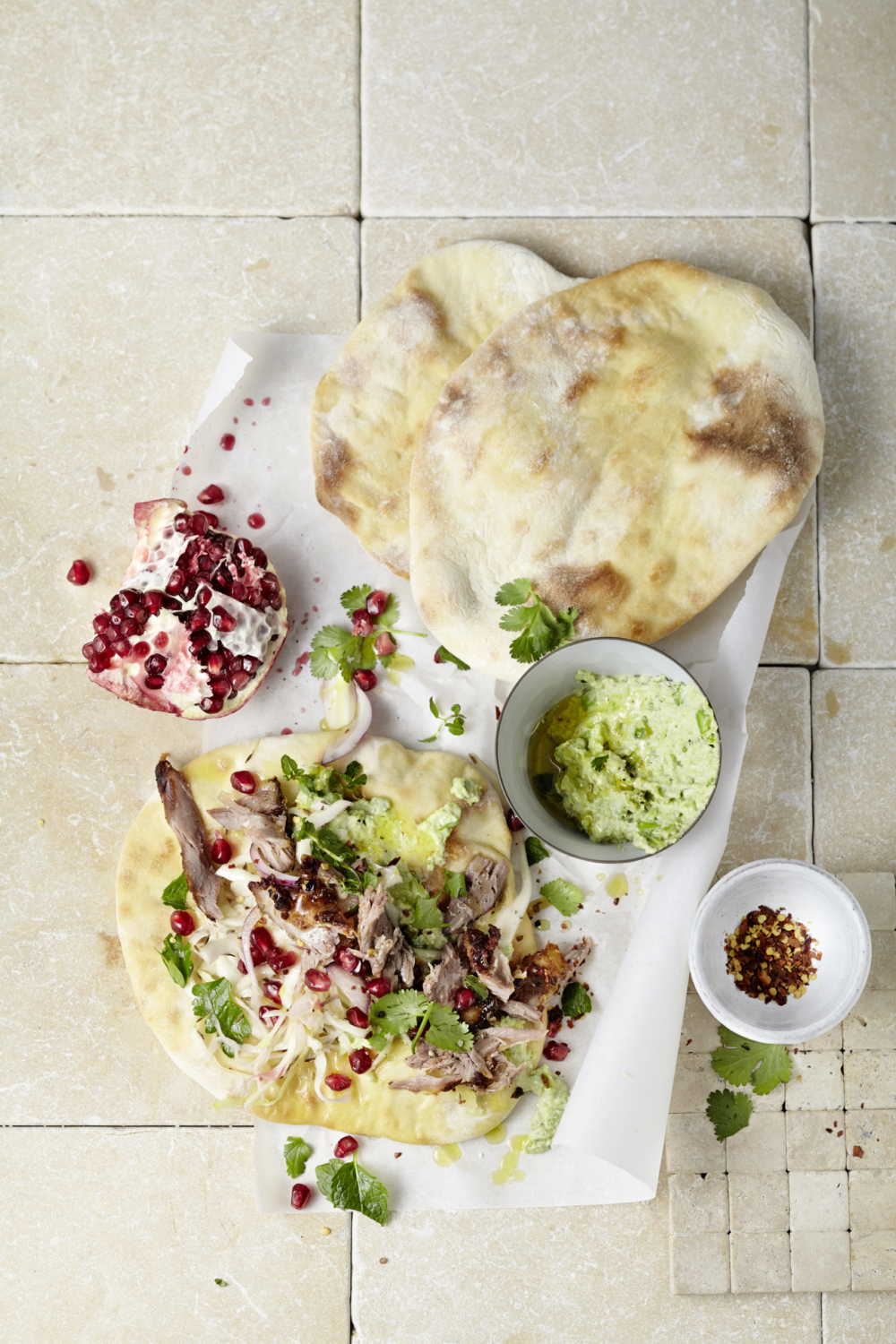 Pulled Lammstelze mit Bio-Hummus & Flat Bread auf einem Tisch.