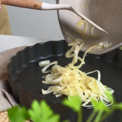 Zwiebel werden von einer Pfanne in eine Auflaufform gegeben!