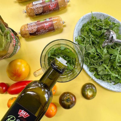 Öl wird in ein Gefäß mit Kräutern gegossen.