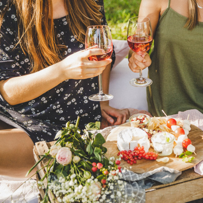 Zwei Frauen stoßen mit Bio-Zweigelt bei einem Picknick an.