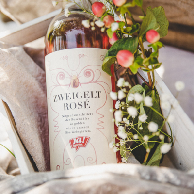 Nahaufnahme von Ja! Natürlich Bio-Zweigelt Rosé in einer Holzkiste mit Blütenknospen.