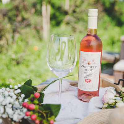 Eine Flasche Ja! Natürlich Bio-Zweigelt Rosé und ein Weinglas.
