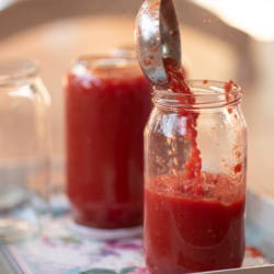 Passierte Tomaten werden in ein Glas abgefüllt