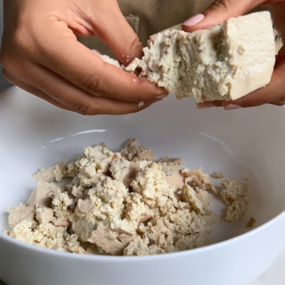 Tofu wird in eine Schale gekrümelt