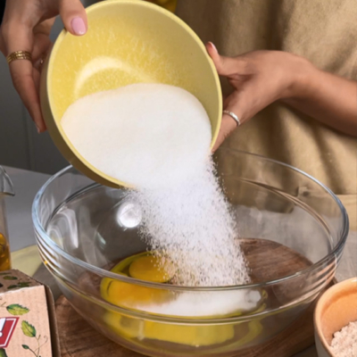 Zucker wird in eine Rührschüssel mit Eiern gegeben