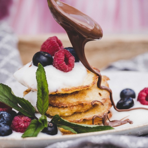 Jemand tröpfelt Nougatcreme über Pfannkuchen.
