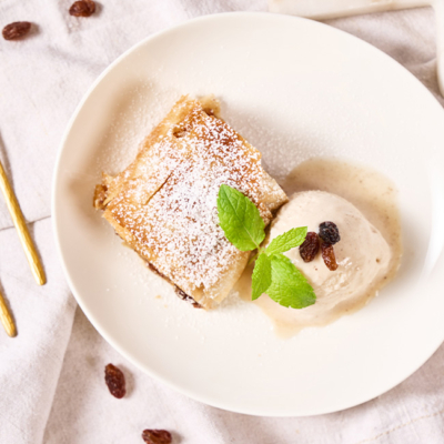 Ein Stück Apfelstrudel auf einem Teller mit Vanille Eis angerichtet