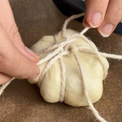 Teig mit einer Schnur zu einem Kürbis binden