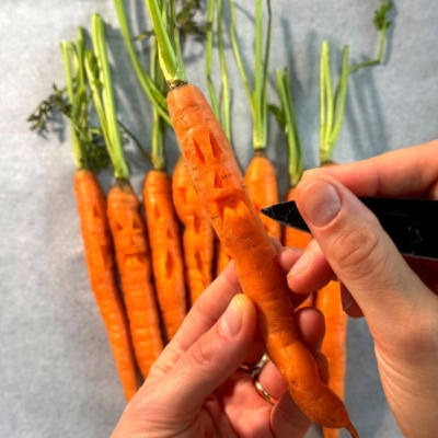 Es werden gruselige Gesichter in Karotten geschnitzt
