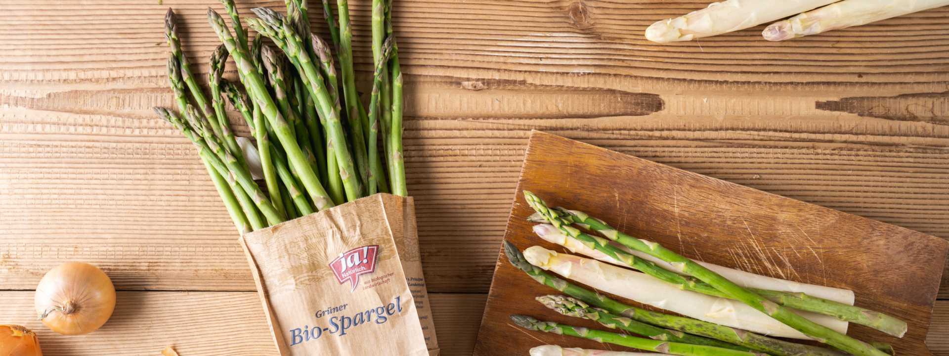 Eine Packung Ja! Natürlich Bio-Spargel neben einem Schneidebrett mit Spargel.